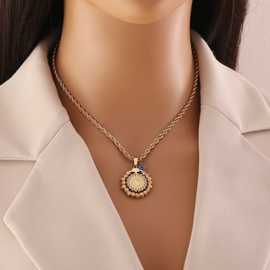 Gold coin pendant necklace with blue evil eye charm and twisted chain on model