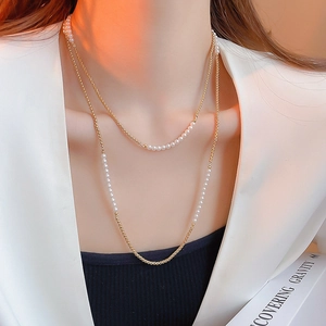 Détail du collier double rang avec chaîne dorée et perles blanches au style rétro français