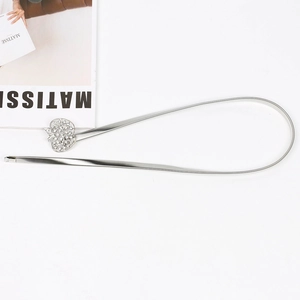 Détail de la ceinture chaîne élastique argentée avec boucle pomme ornée de strass brillants