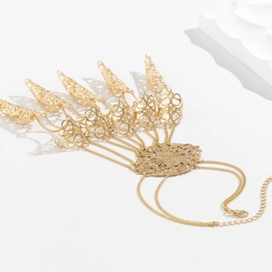 Close-up of golden punk gothic claw bracelet with hollow patterns and cone fringe chains