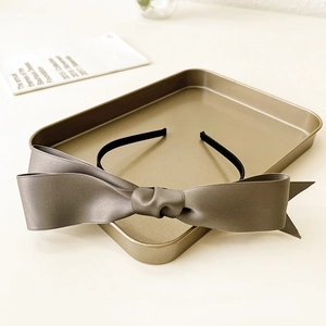 Detail of grey satin double bow headband on a gold tray with elegant minimalist texture