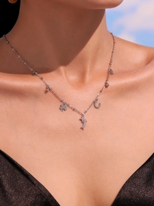Close-up of 18k gold dolphin and infinity charms on a layered stainless steel necklace