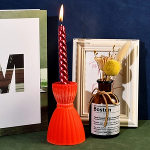 Macro view of a red spiral candle set on a pleated orange resin base for home decor