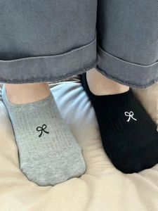 Detail of grey and black cotton boat socks with white bow embroidery and ribbed texture