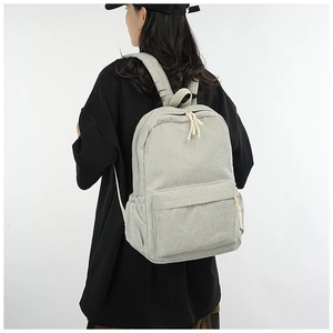 Rear view of a light gray corduroy backpack worn on shoulders for a minimalist look