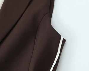 Detailed view of dark brown fabric with clean white piping on shoulder and side seams