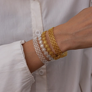 Close-up of stacked gold and silver filigree flower bangles on a model wrist