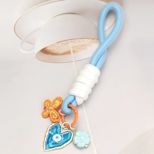 Détail du porte-clés tressé œil bleu avec breloques de papillon orange et petite fleur