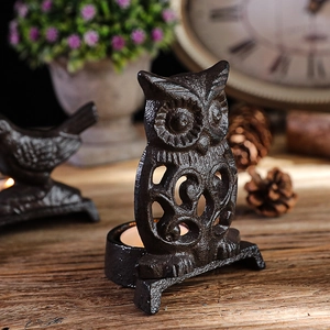 Vintage owl cast iron candle holder with cutout design on a rustic wooden table setup