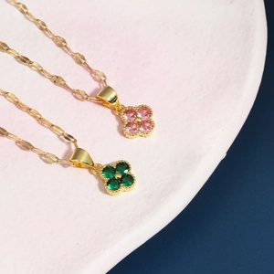 Dettaglio macro di collane a quadrifoglio in oro con gemme sfaccettate rosa e verdi