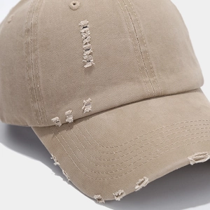 Macro view of distressed khaki baseball cap featuring vintage frayed details and stitching