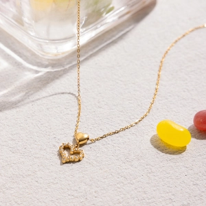 Close-up of gold bow necklace with heart pendant and sparkling clear gemstone