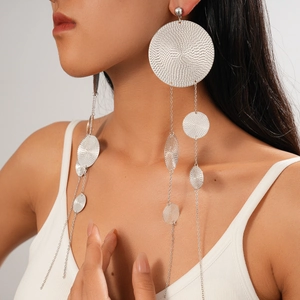 Detailed view of silver layered chain fringe earrings with circular textured metal pendants