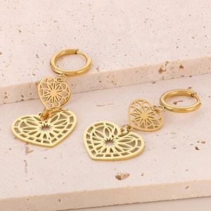 Detail von goldenen hohlen Herzohrringen auf einer strukturierten Steinoberfläche
