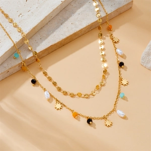 Double-layered gold necklace with pearls, colorful beads and star pendant on stone