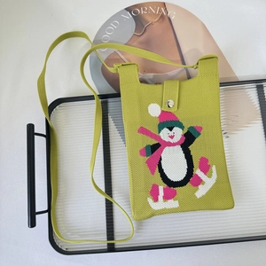 Detail of green knit penguin crossbody bag featuring pink scarf and magnetic snap closure