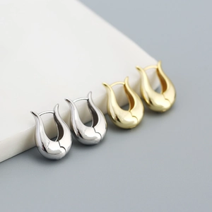 Close-up of minimalist U-shaped sterling silver earrings in gold and silver finish