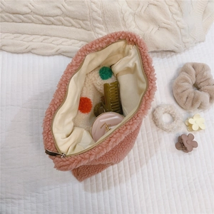 Interior view of soft pink sherpa makeup bag showing spacious storage with toiletries
