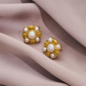 Macro détaillée de boucles d'oreilles vintage dorées avec perles sur soie