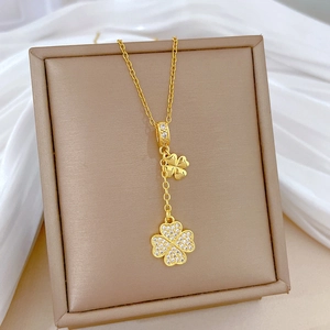 Elegant gold clover tassel necklace with crystal pavé pendants on a silk background