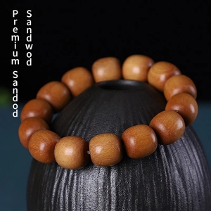 Bracelet en bois de santal Barbie avec douze perles cylindriques brunes sur un vase en céramique