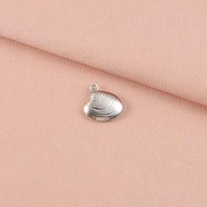 Detail view of silver stainless steel shell pendant with texture on pink fabric