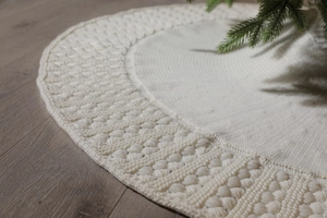 Close-up of cream knitted Christmas tree skirt featuring 3D textured ball pattern