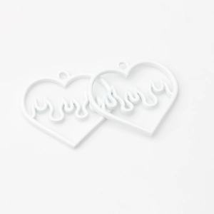 Macro shot of two white alloy heart flame pendants for minimalist DIY jewelry making