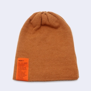 Detailed knit texture of a brown winter beanie with a stylish orange slogan label