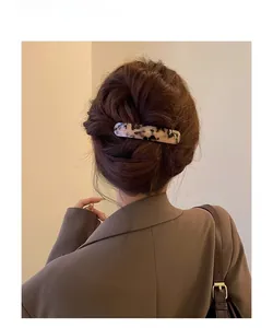 Detail of amber marble pattern spring hair clip worn on long wavy brown hair