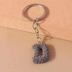 Detailed view of creative grey resin rose-textured letter D keychain with silver ring