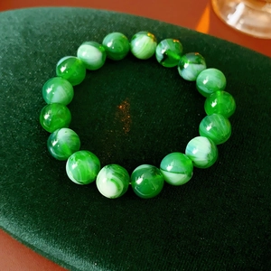 Detailed shot of green stone beaded bracelet with marble texture on velvet display