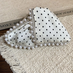 Detailed macro view of the polka dot hair claw clip with pearl trim on woven mat