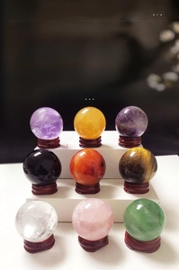 Detailed set of nine natural crystal spheres on wooden stands including amethyst and quartz