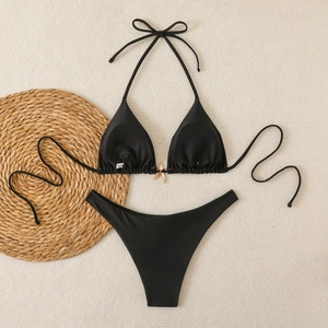 Detail of black bikini top featuring a central golden starfish ornament and halter neck
