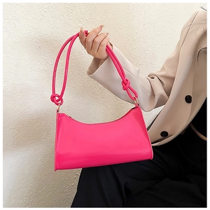 Detail of fuchsia glossy baguette bag featuring knotted straps and golden metal hardware