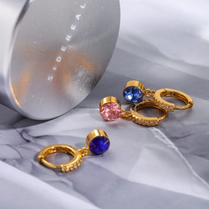 Primer plano de pendientes de aro dorados con gemas azules y rosas y pavé de circonitas