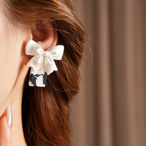 Gros plan d'un mannequin portant des boucles d'oreilles nœud au motif marbre noir et blanc