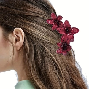 Detail view of a burgundy floral hair claw clip worn on hair with realistic styling