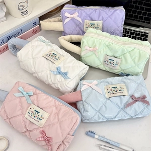 Quilted macaron pouches with bows and HAPPY patches shown on an office desk setup