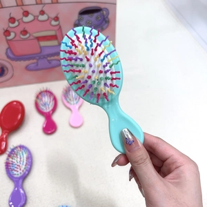 Detail of colorful rainbow wavy bristles on a blue portable mini cushion hairbrush