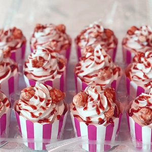 Caissettes à muffins rayées roses avec cupcakes et crème dans une boîte transparente