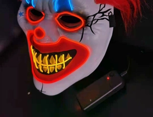 Close-up of LED glowing clown mask with red and blue light wires in dark background