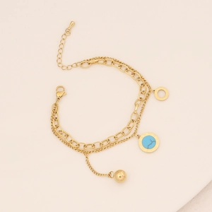 Detail view of gold layered turquoise necklace with sunburst pendant and metal ball charm