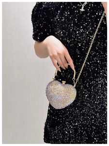 Macro shot of heart evening bag with multi-color rhinestones and golden ring handle