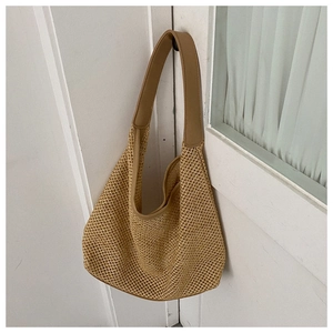 Detail of khaki woven straw shoulder bag featuring a wide PU leather strap and hollow pattern