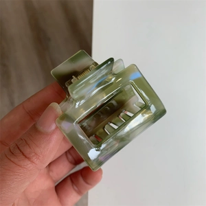 Detail showing high-gloss green marble texture on square acetate hair claw clip