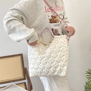 Sac à main matelassé à fleurs porté par un mannequin avec bandoulière rose amovible