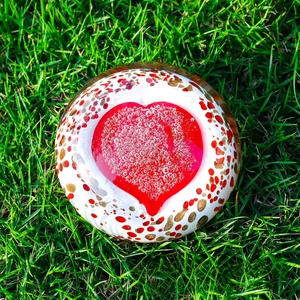 Macro shot of glass paperweight with red heart and artistic gold bubbles texture