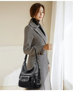 Detail of black soft leather crossbody bag with multiple silver zipper pockets on model